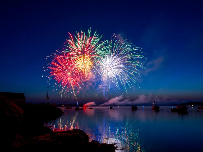 Wir sehen ein buntes Feuerwerk über einem Fluß