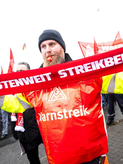 Ein Mann hält bei der Streikkundgebung von der IG Metall vor dem Volkswagen-Werk  in Emden einen Schal mit der Aufschrift "Küstenweit Streikbereit" am 2.Dezember 2024.