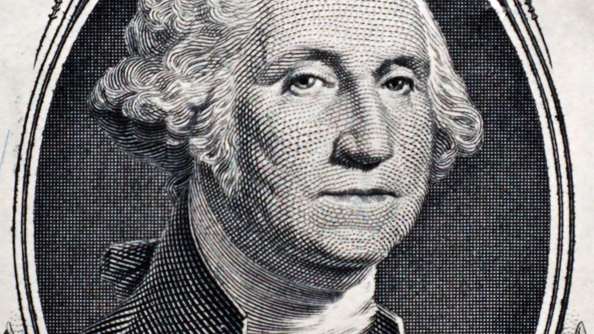 Ausschnitt auf der 1-US-Dollar-Note, auf der ein Porträt von George Washington gedruckt ist. Das Porträt ist umrandet von Ornamenten. Ausschnitt auf der 1-US-Dollar-Note, auf der ein Porträt von George Washington gedruckt ist. Das Porträt ist umrandet von Ornamenten.