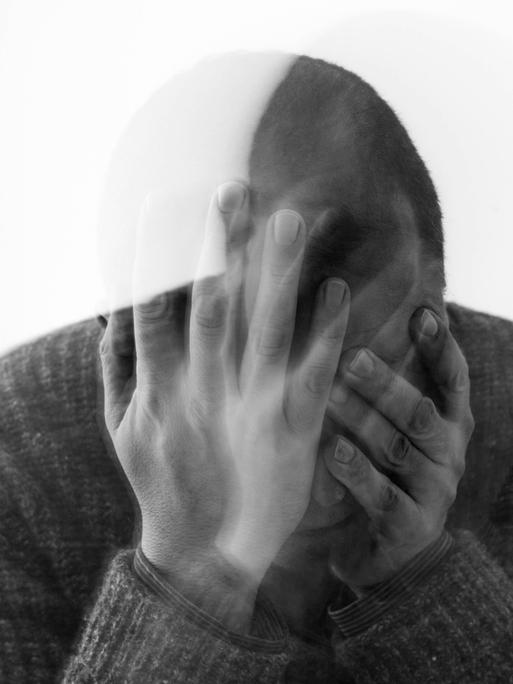 Alles verschwommen, grau und trüb: Ein mittelalter Mann mit schütterem Haar stützt den Kopf in seine Hände. So wie auf einem Symbolbild fühlt sich für viele Betroffene Depression an. 