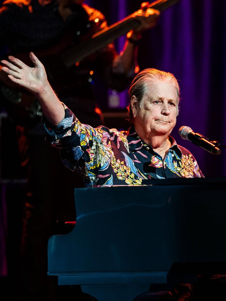 Brian Wilson sitzt in einem bunten Hemd am Konzertflügel, im Hintergrund die Band.