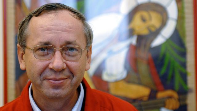 Marko Rupnik vor einem seiner Mosike, das eine Christusfigur mit Heiligenschein zeigt