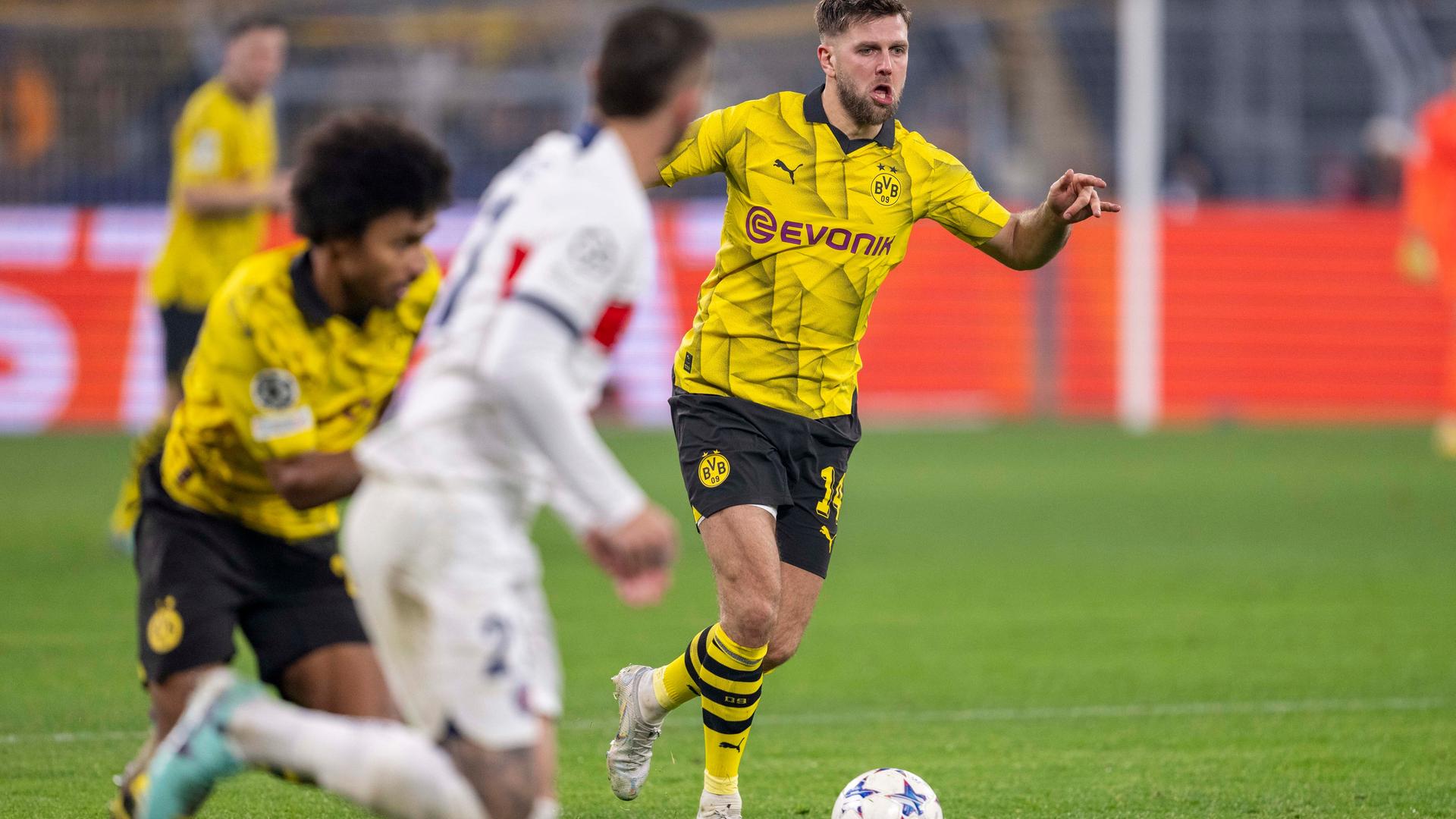 Niclas Füllkrug im Dortmund-Trikot am Ball, neben ihm sind weitere Dortmunder sowie ein Pariser Spieler im Bild.