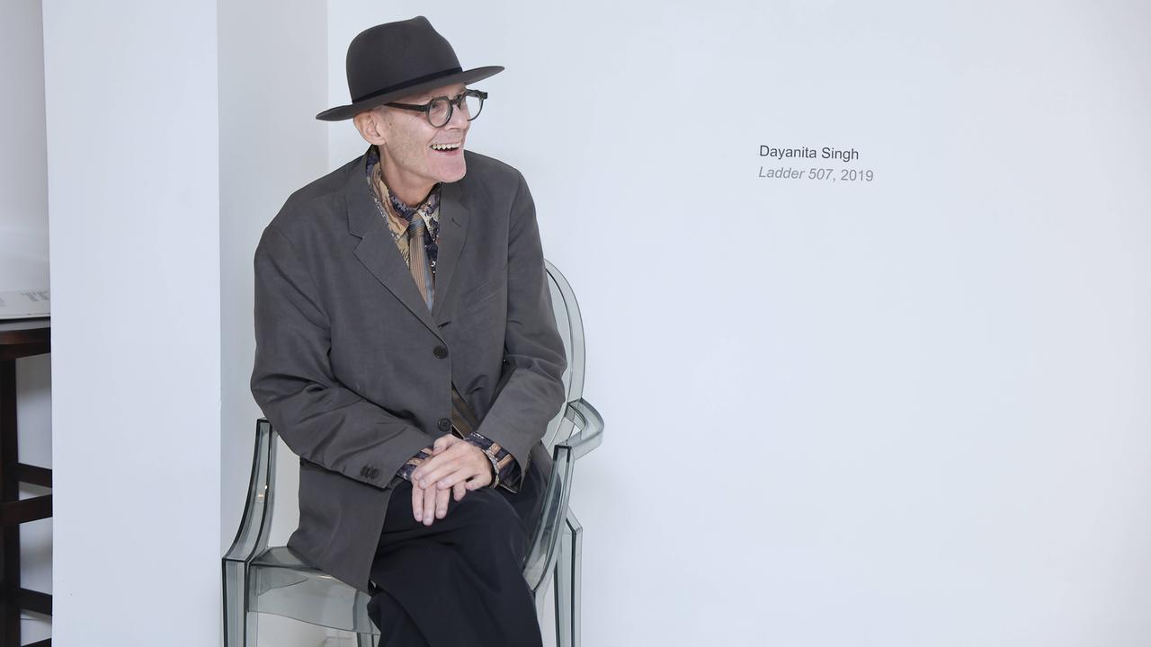 Peter Nagy sitzt in seiner Gallerie auf einem Stuhl und lächelt.