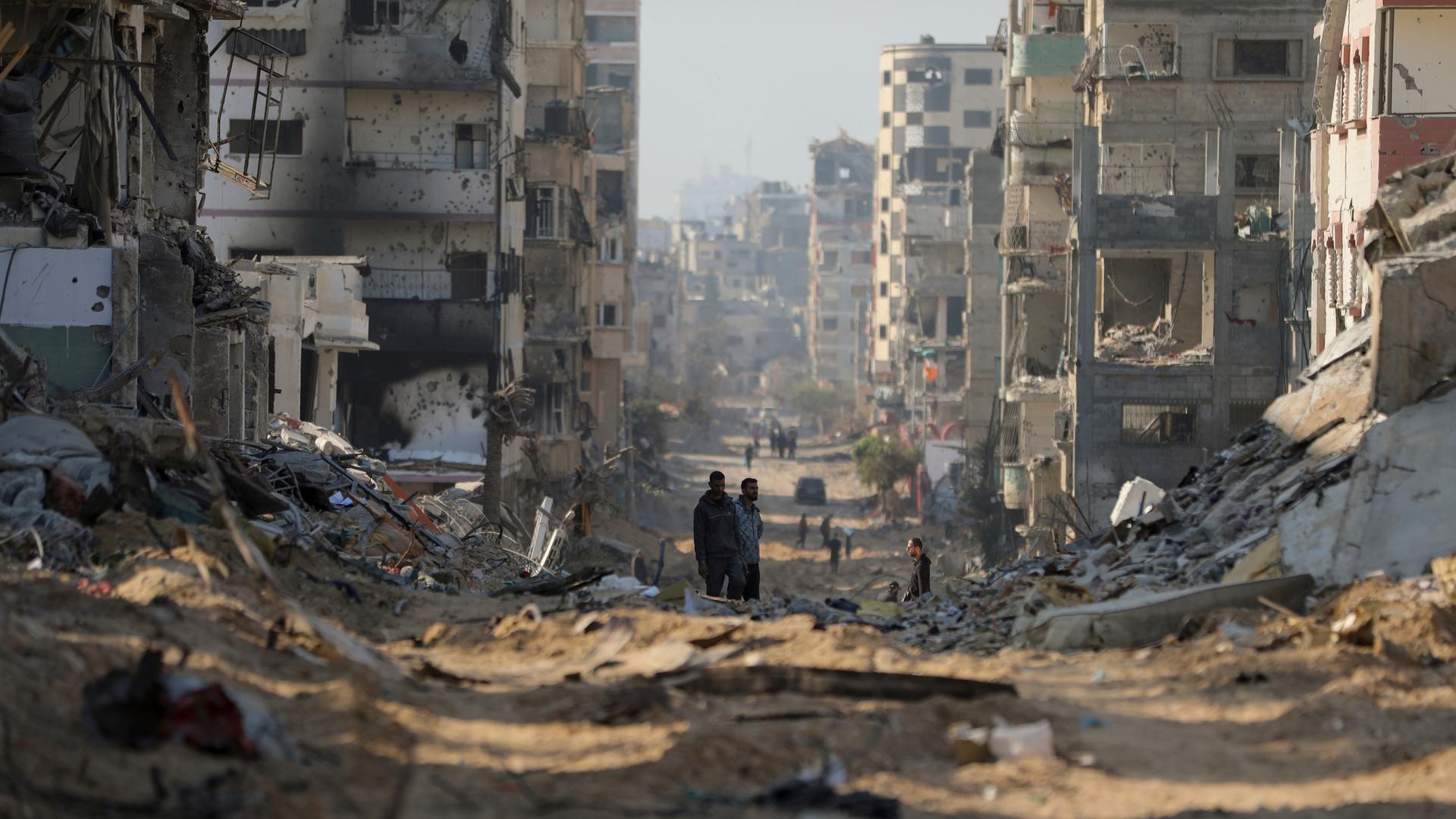 Palästinenser gehen an den Überresten zerstörter Gebäude in Gaza-Stadt vorbei.