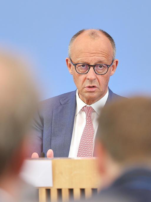 Friedrich Merz sitzt vor dem blauen Hintergrund der Bundespressekonferenz und spricht mit Journalisten. Friedrich Merz sitzt vor dem blauen Hintergrund der Bundespressekonferenz und spricht mit Journalisten.