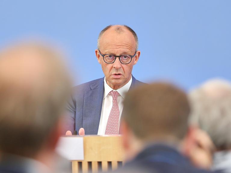 Friedrich Merz sitzt vor dem blauen Hintergrund der Bundespressekonferenz und spricht mit Journalisten. Friedrich Merz sitzt vor dem blauen Hintergrund der Bundespressekonferenz und spricht mit Journalisten.