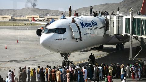 Afghanische Menschen klettern auf ein Flugzeug auf dem Flughafen in Kabul im August 2021. Sie versuchen verzweifelt zu fliehen, weil die Taliban die Macht übernommen haben.