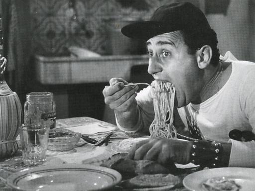 Schwarz-weiß Bild: Der italienische Schauspieler Alberto Sordi isst Spaghetti (1954).