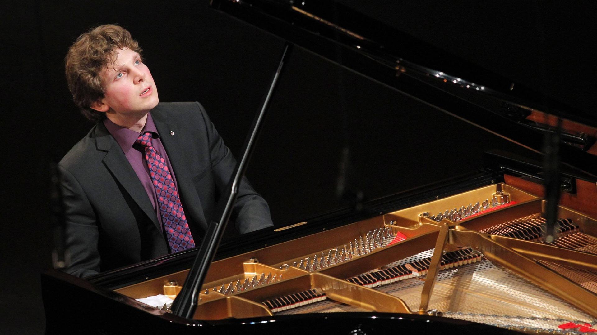 Der britisch-australische Pianist Jayson Gillham sitz an einem offenen Flügel, spielt und blickt nach oben Der britisch-australische Pianist Jayson Gillham sitz an einem offenen Flügel, spielt und blickt nach oben