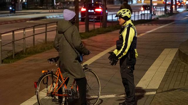 Das Foto zeigt eine Frau auf dem Fahrrad. Ein Polizist kontrolliert die Frau.