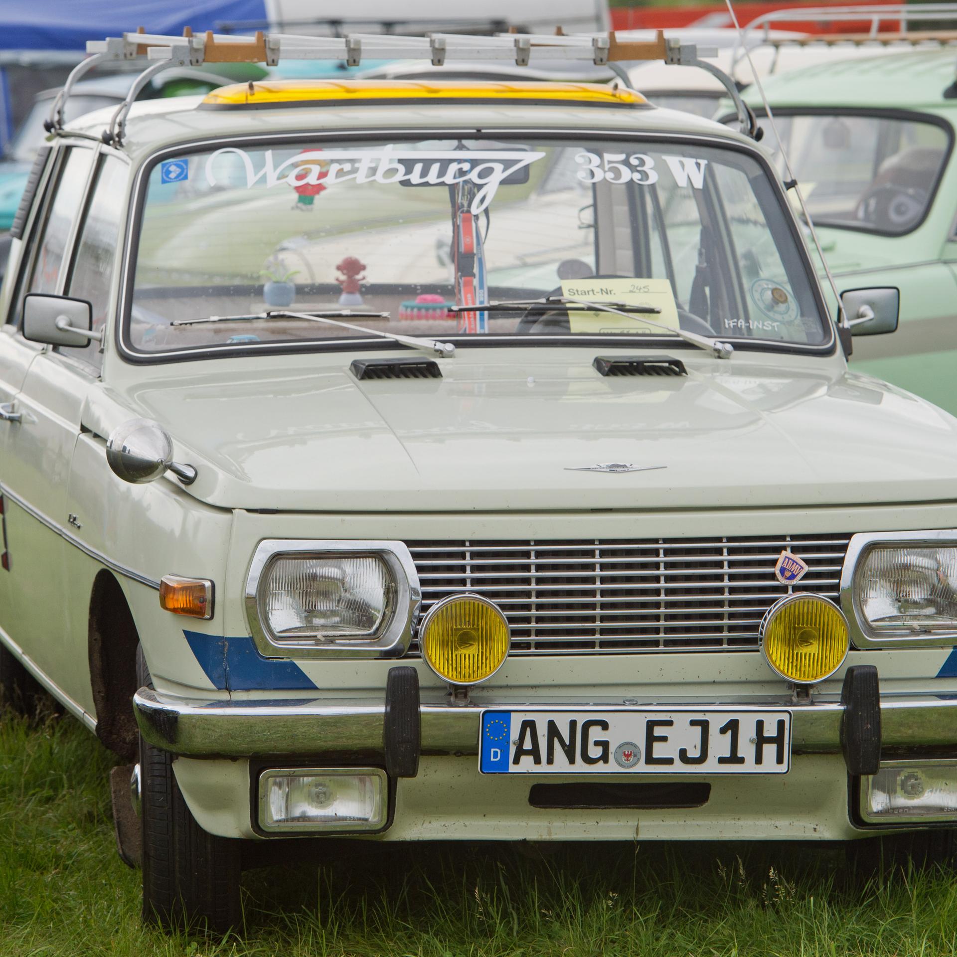 Ein Wartburg 353 W (W = Weiterentwicklung) steht auf einer Wiese zusammen mit anderen Autos.