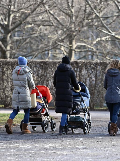 Junge Mütter schieben ihre Kinderwägen durch den Hofgarten in München 