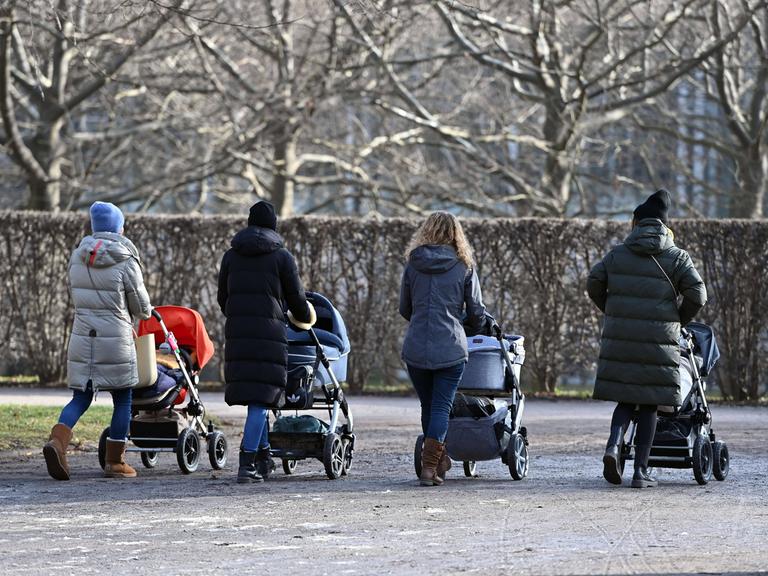 Junge Mütter schieben ihre Kinderwägen durch den Hofgarten in München 