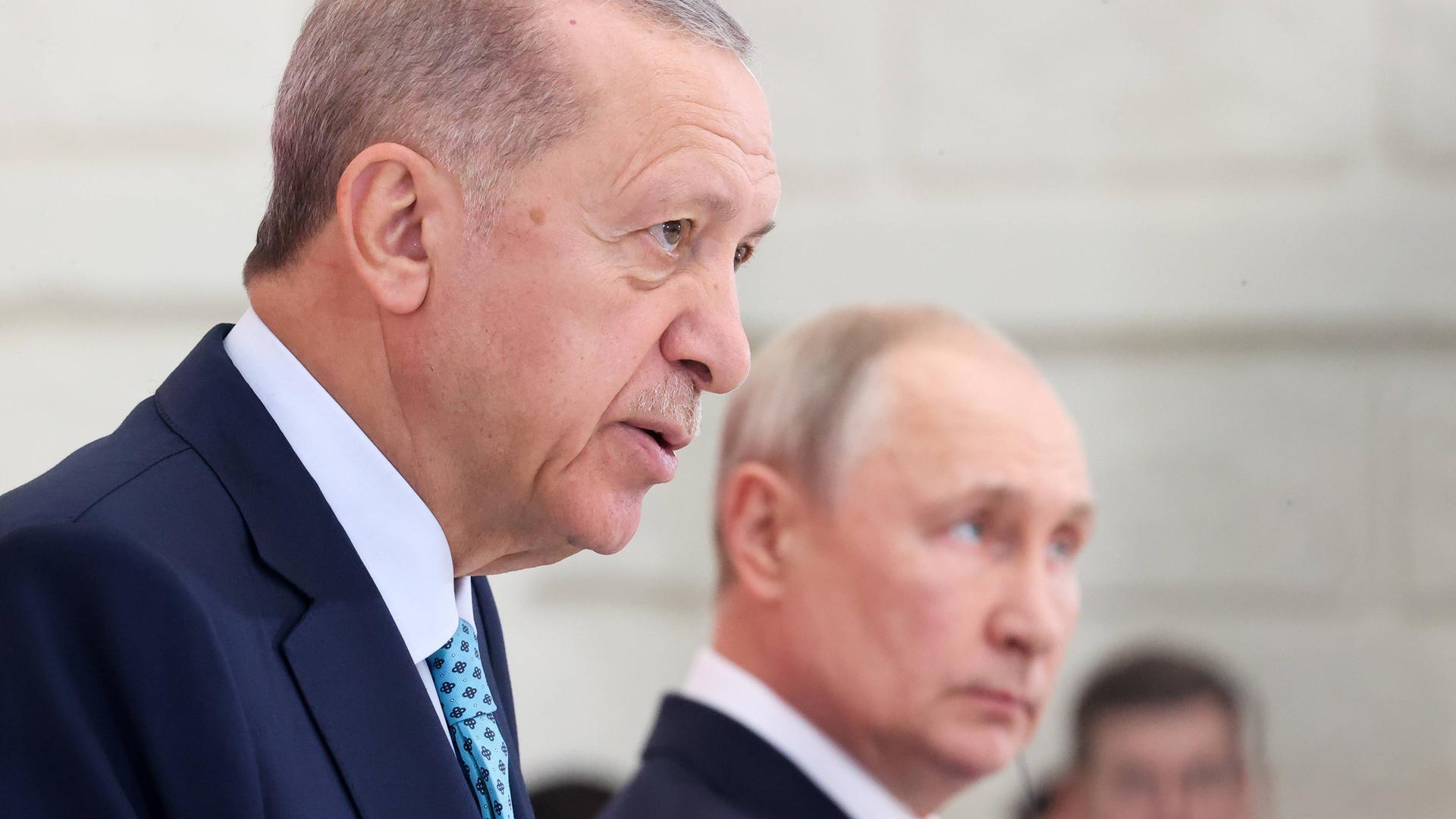 Erdogan und Putin nebeneinander in einem Raum. Sie sind schräg von der Seite fotografiert.