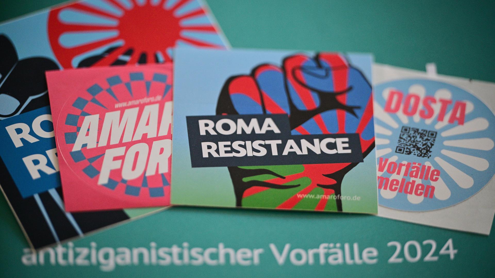 Aufkleber etwa mit der Aufschrift "Roma Resistance" liegen während einer Pressekonferenz zur Auswertung der Dokumentationsstelle Antiziganismus (MIA) Berlin auf einer Ausgabe des Kurzberichts zu antiziganistischen Vorfällen 2024. Aufkleber etwa mit der Aufschrift "Roma Resistance" liegen während einer Pressekonferenz zur Auswertung der Dokumentationsstelle Antiziganismus (MIA) Berlin auf einer Ausgabe des Kurzberichts zu antiziganistischen Vorfällen 2024.