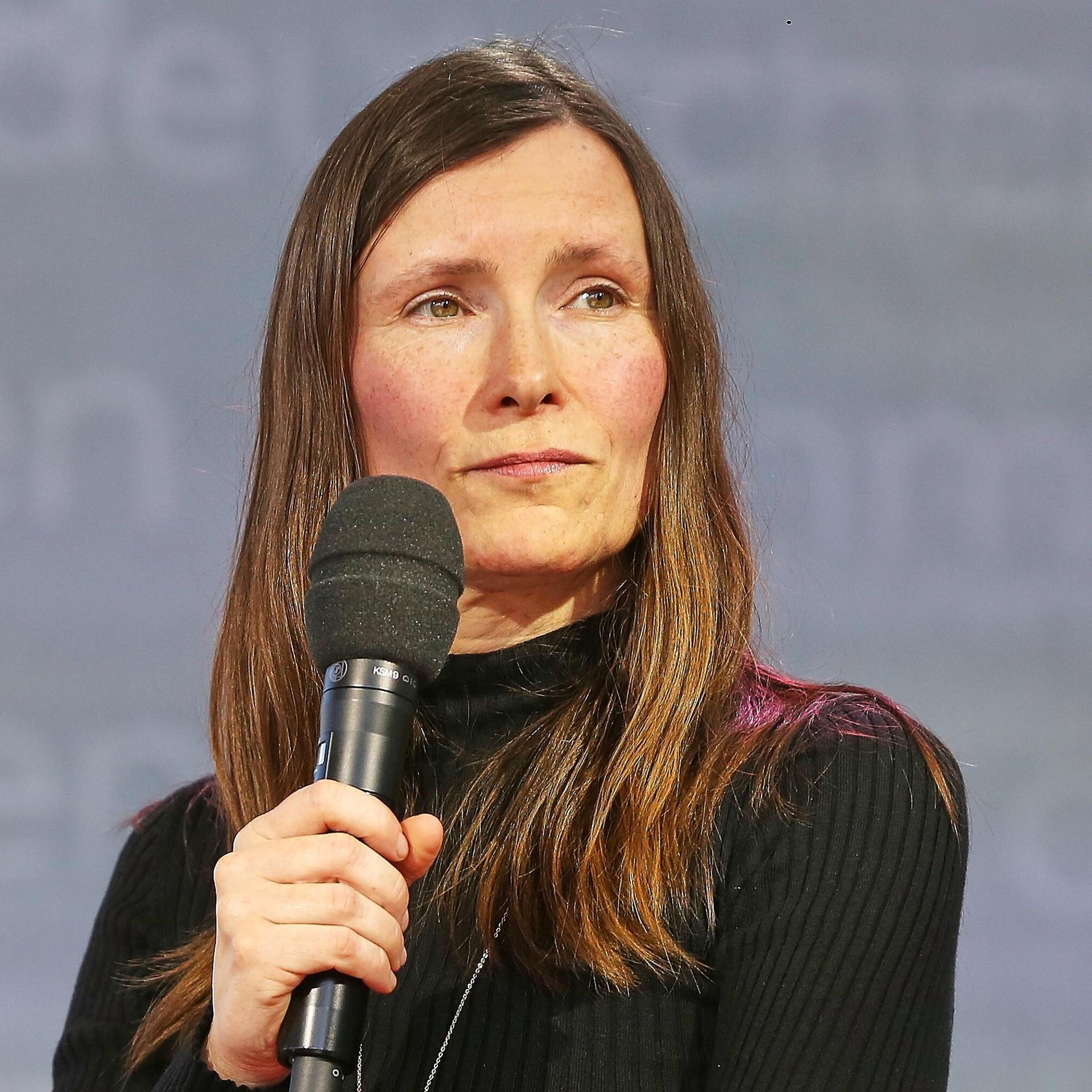 Heike Geißler mit langen braunen Haaren guckt mit einem Mikrofon in der Hand auf der Leipziger Buchmesse zur Seite