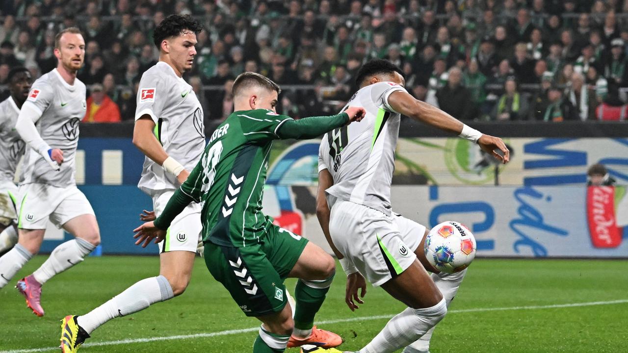 Beim Fußball-Bundesligaspiel zwischen SV Werder Bremen und dem VfL Wolfsburg liefert sich der Bremer Romano Schmid einen Zweikampf mit dem Wolfsburger Moritz Jenz. Im Hintergrund sind zwei weitere Wolfsburger Spieler zu sehen.