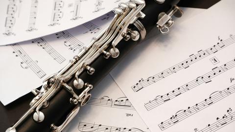 Wir sehen die Nahaufnahme einer Oboe, die auf beschriebenen Notenblättern liegt