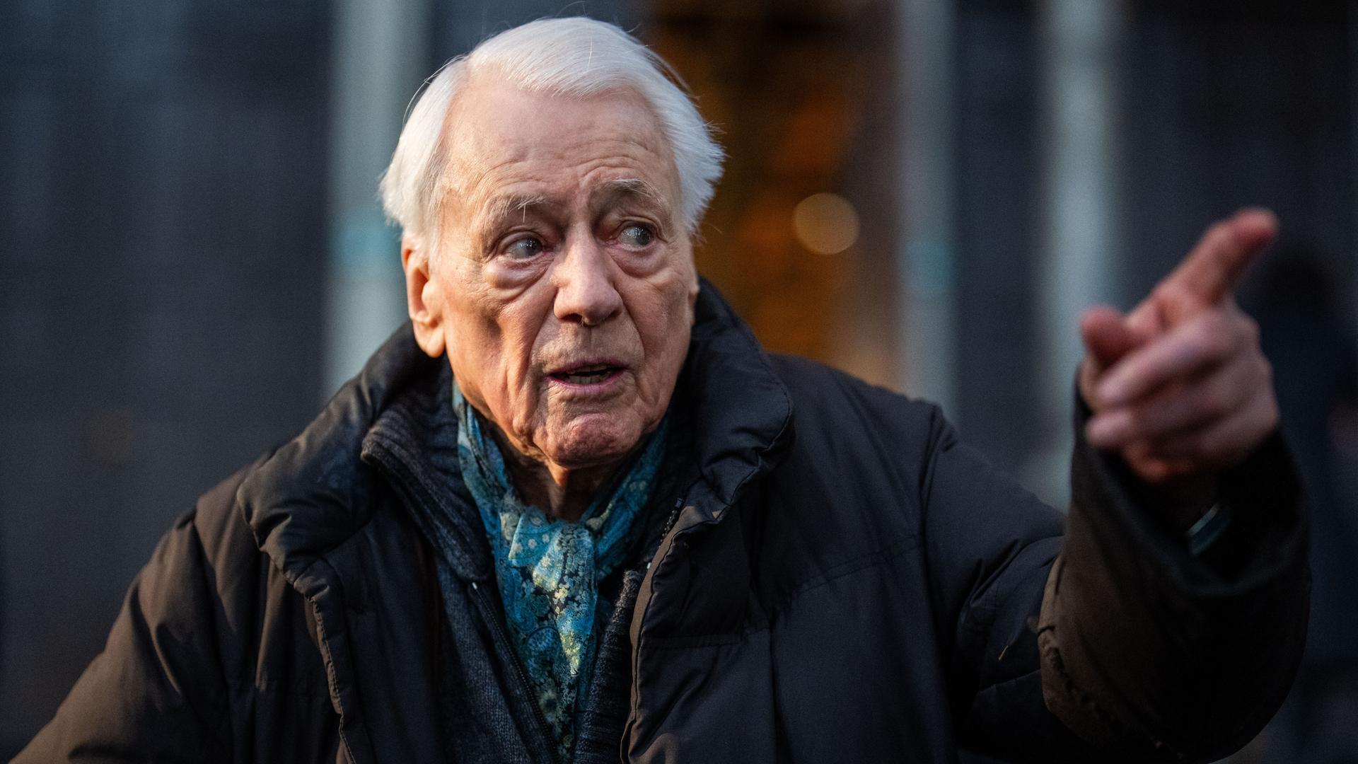 Alexander Kluge steht in einem Museum und deutet auf etwas außerhalb des Bildes Alexander Kluge steht in einem Museum und deutet auf etwas außerhalb des Bildes