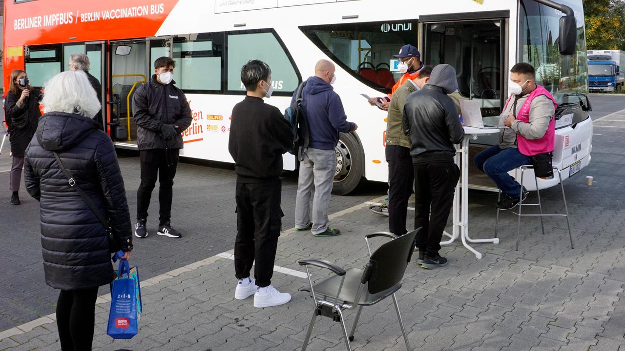 Menschen warten vor einem Berliner Impfbus am Dong Xuan Center im Berliner Stadtteil Lichtenberg. 