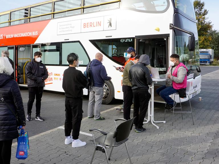 Menschen warten vor einem Berliner Impfbus am Dong Xuan Center im Berliner Stadtteil Lichtenberg. 
