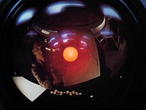 Szene aus "Odyssee im Weltraum" von Stanley Kubrick. Das Gesicht eines Mannes spiegelt sich in Glas. 