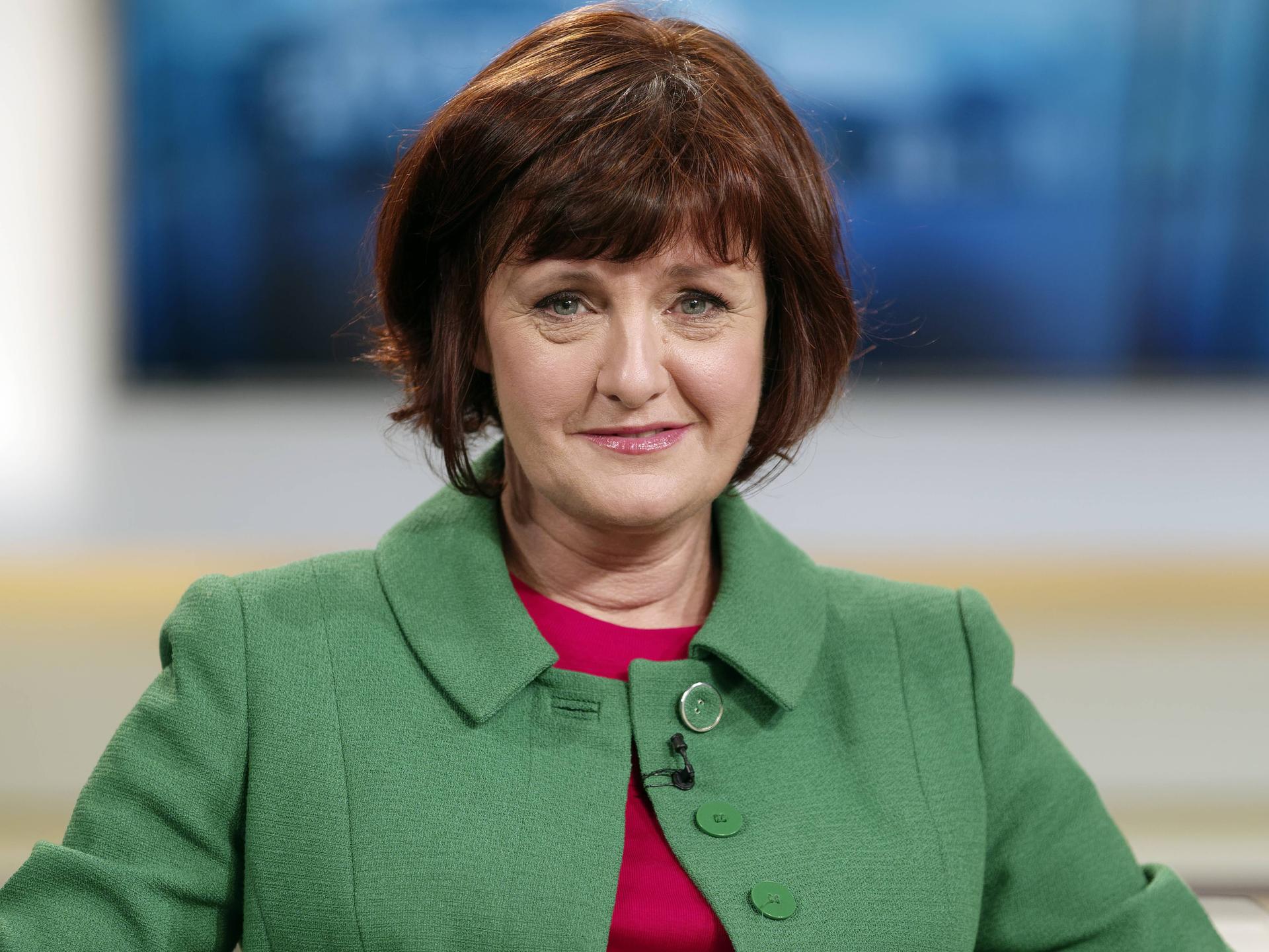 Porträt von Annette Dittert, die ehemalige Leiterin des ARD-Studios in London. Sie trägt einen Pagenschnitt und eine grüne Jacke und sitzt in einem Fernsehstudio