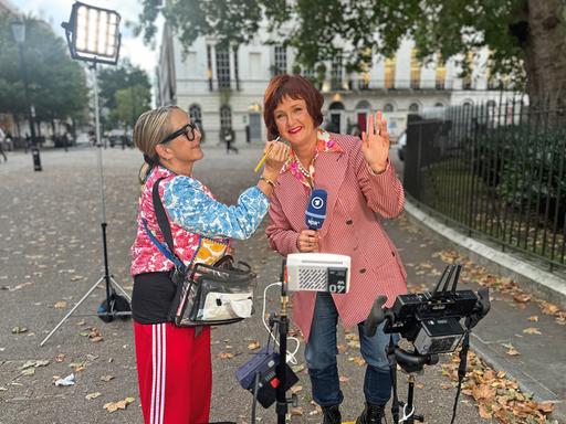 Porträt von Annette Dittert, die ehemalige Leiterin des ARD-Studios in London. Sie trägt einen Pagenschnitt und eine grüne Jacke und sitzt in einem Fernsehstudio