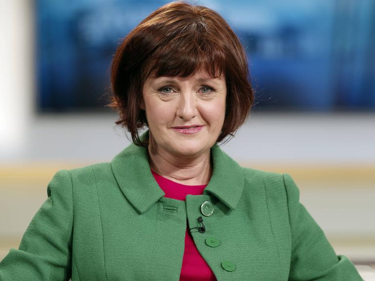 Porträt von Annette Dittert, die ehemalige Leiterin des ARD-Studios in London. Sie trägt einen Pagenschnitt und eine grüne Jacke und sitzt in einem Fernsehstudio