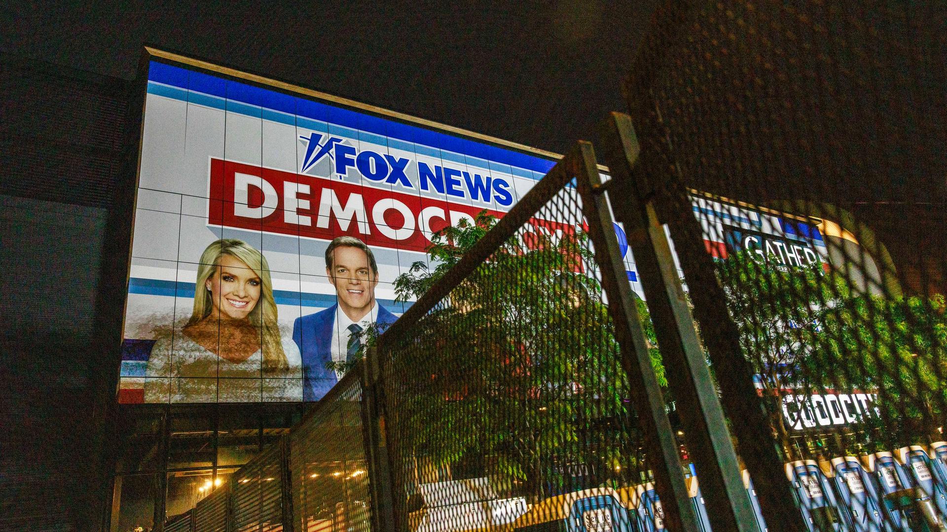 Ein Banner von Fox News hängt an einem Gebäude. Darauf zu sehen: eine Frau und ein Mann sowie der Schriftzug „Fox News“ und „Democracy“. 