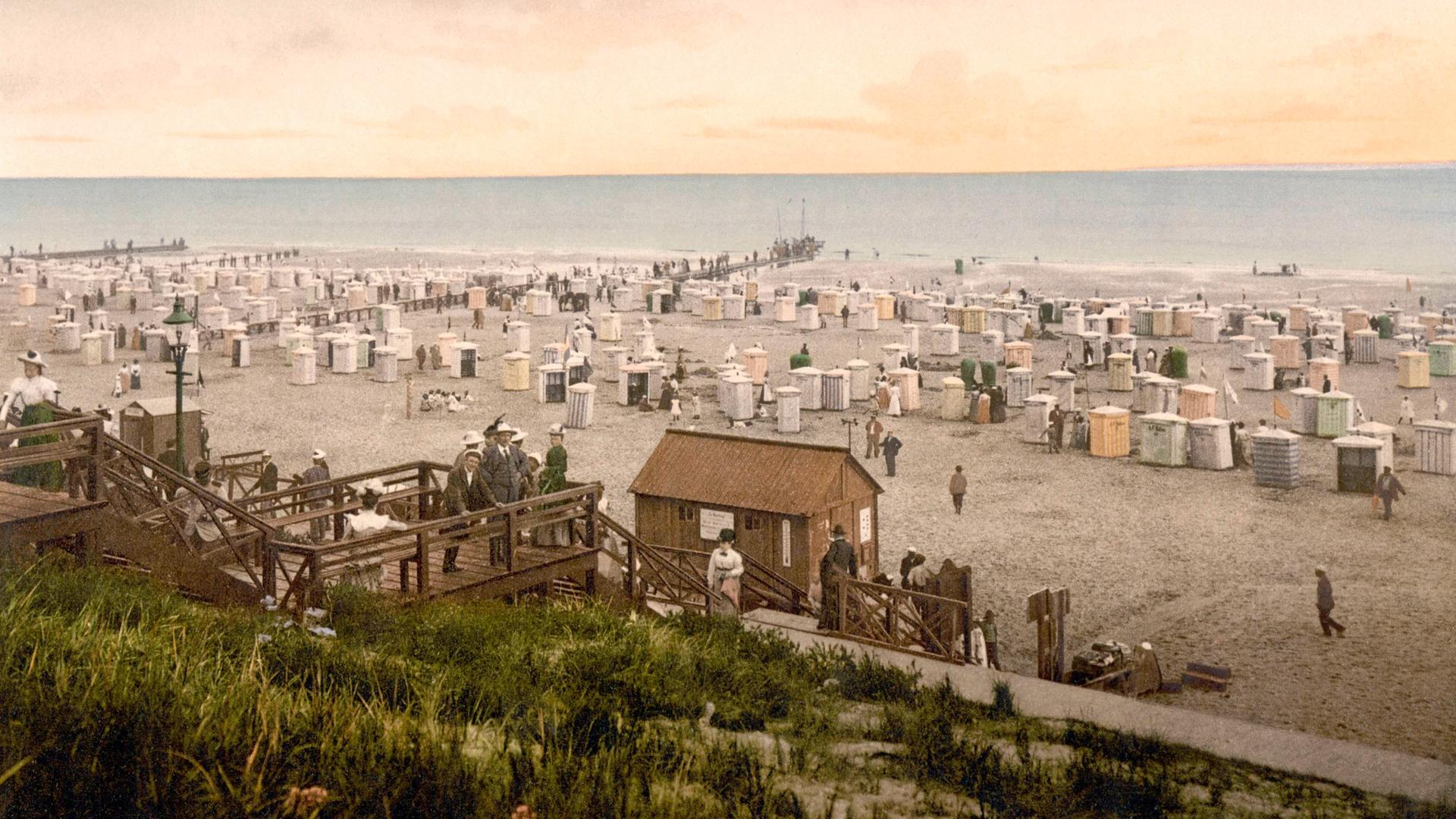 Nachkolorierte historische Aufnahme zeigt den Strand von Borkum mit Kurgästen um 1900. 