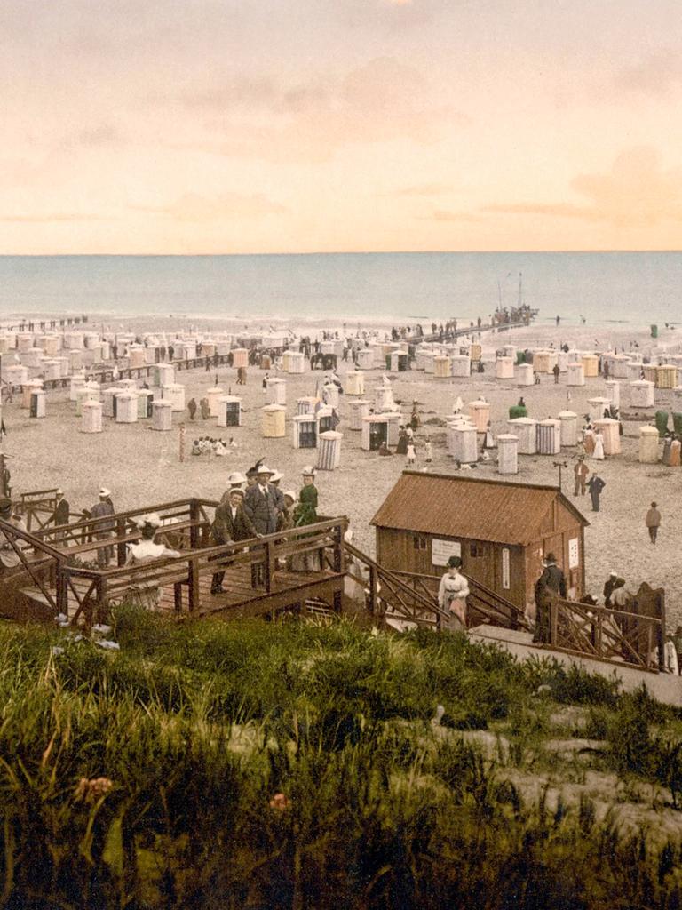 Nachkolorierte historische Aufnahme zeigt den Strand von Borkum mit Kurgästen um 1900. 