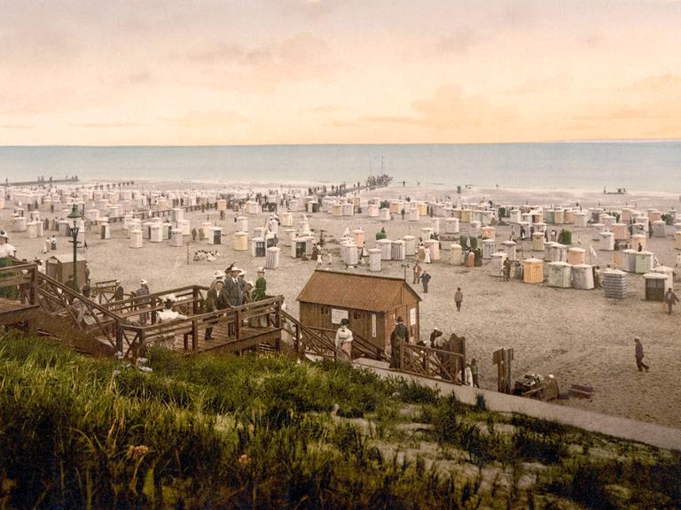 Nachkolorierte historische Aufnahme zeigt den Strand von Borkum mit Kurgästen um 1900. 