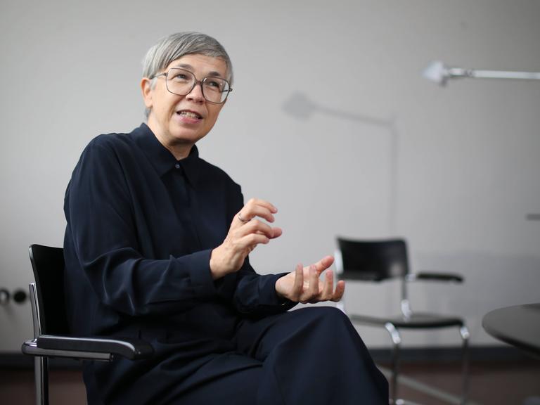 Barbara Steiner sitzt lächelnd und gestikulierend in einem Bürostuhl.