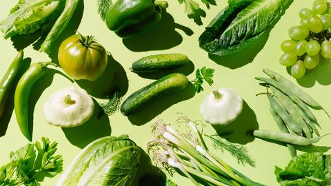 Frisches grünes Bio-Gemüse und Obst auf hellgrünem Hintergrund.