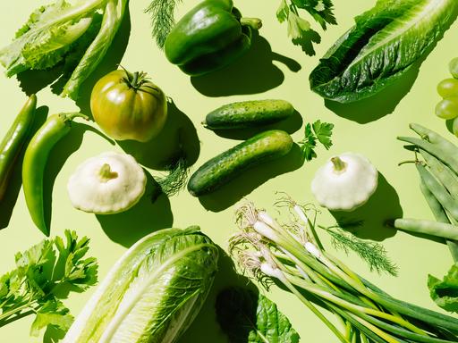Frisches grünes Bio-Gemüse und Obst auf hellgrünem Hintergrund.