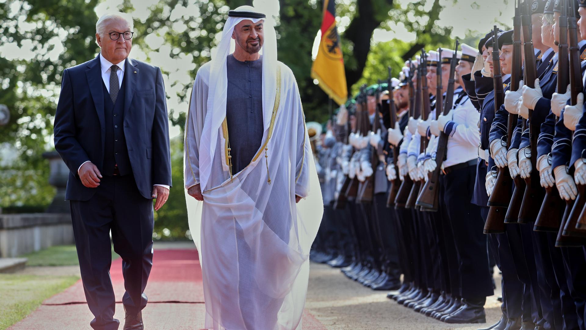Scheich Mohammed bin Sajid und Bundespräsident Steinmeier gehen auf dem roten Teppich an einer Reihe Soldaten entlang.