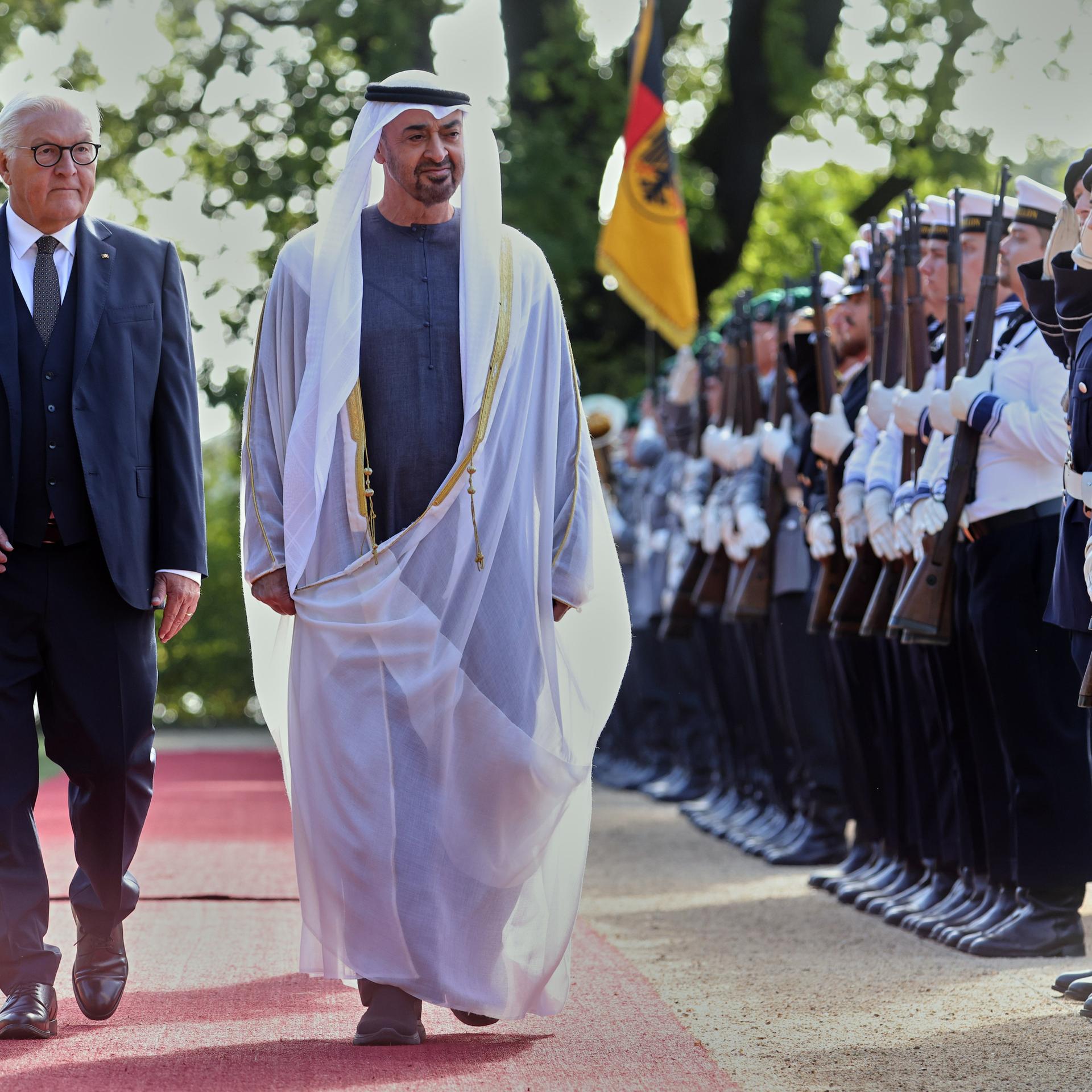 Scheich Mohammed bin Sajid und Bundespräsident Steinmeier gehen auf dem roten Teppich an einer Reihe Soldaten entlang.