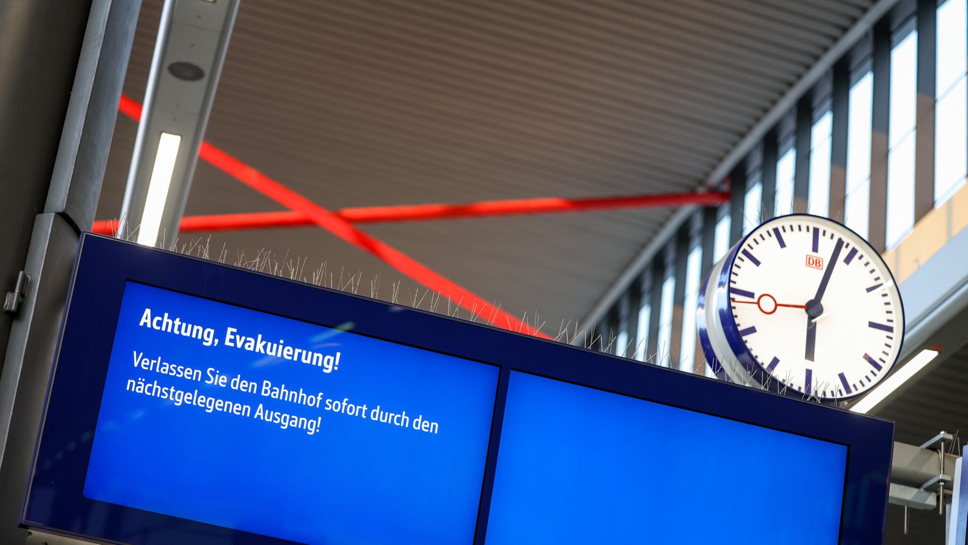 Auf einem Monitor werden Reisende informiert, dass sie den Hauptbahnhof im Rahmen einer Evakuierung zu verlassen haben. 