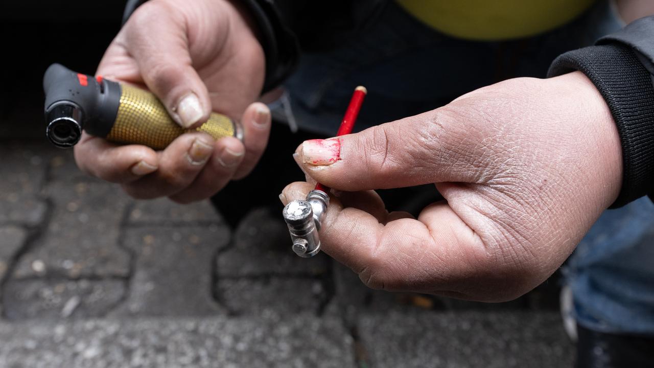 Eine Frau zündet sich auf einer Straße eine Crack-Pfeife an Eine Frau zündet sich auf einer Straße eine Crack-Pfeife an