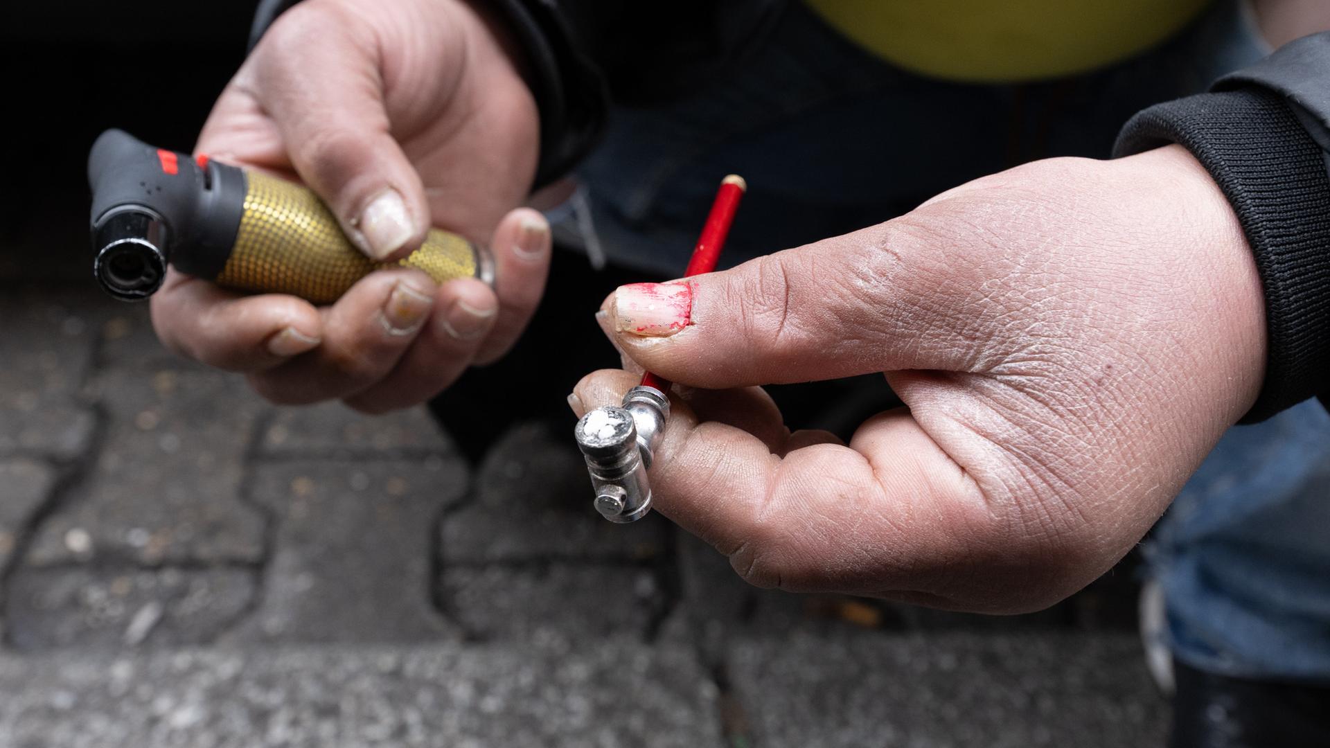 Eine Frau zündet sich auf einer Straße eine Crack-Pfeife an