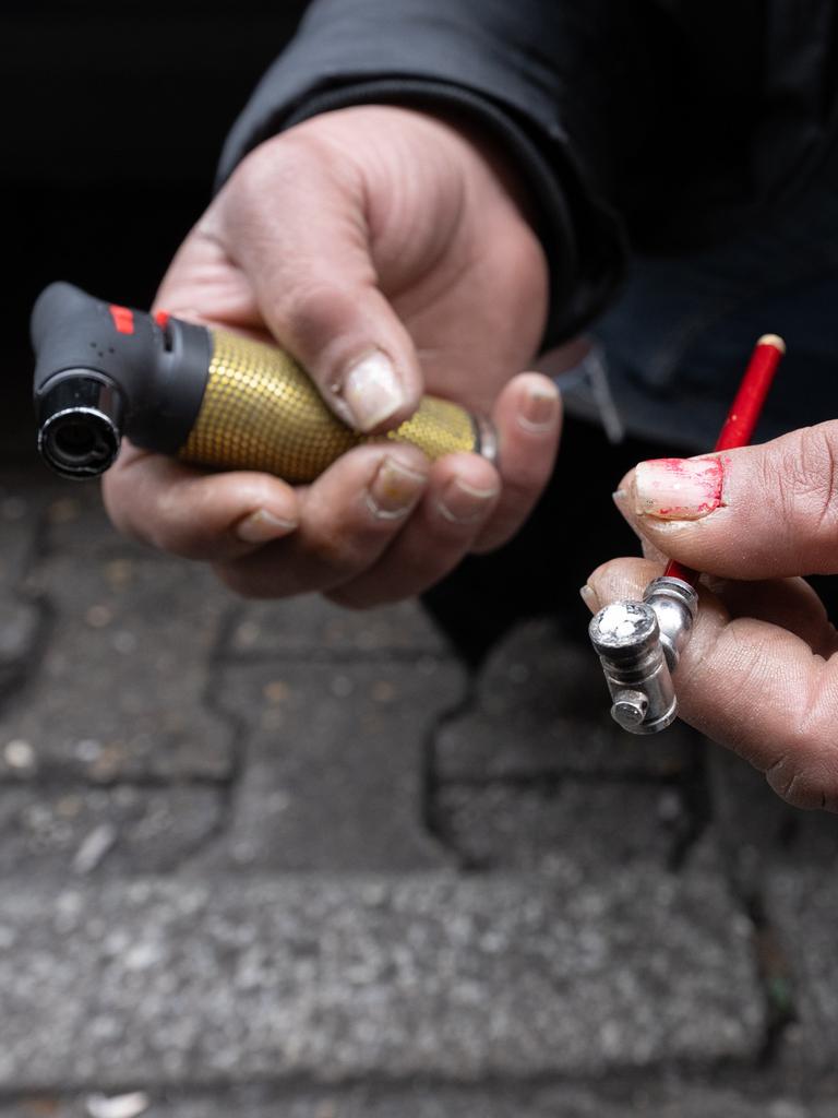 Eine Frau zündet sich auf einer Straße eine Crack-Pfeife an