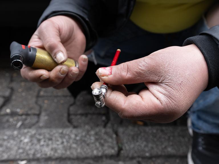 Eine Frau zündet sich auf einer Straße eine Crack-Pfeife an