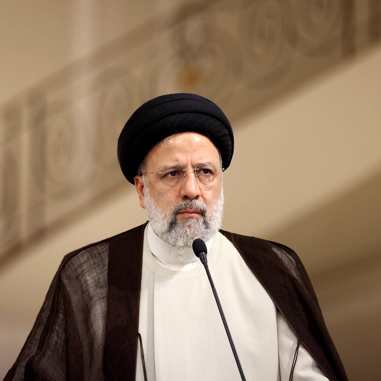Ebrahim Raisi, Präsident der Islamischen Republik Iran, vor einem Mikrofon und neben einer iranischen Flagge Ebrahim Raisi, Präsident der Islamischen Republik Iran, vor einem Mikrofon und neben einer iranischen Flagge
