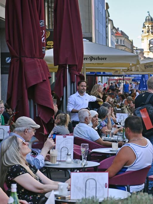 Vollbesetztes Strassencafe in der Weinstrasse in München 