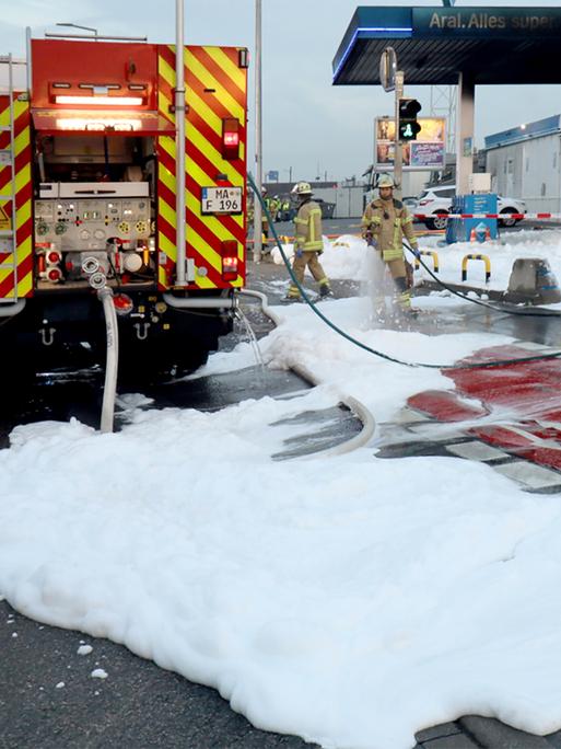 Löschschaum liegt nach dem Einsatz der Feuerwehr auf dem Gelände einer Tankstelle. 
