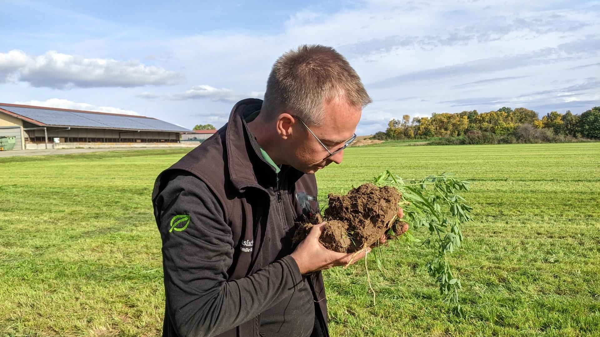 Bio-Landwirt Wolfram Wiggert untersucht den Boden seiner Ackerfläche.