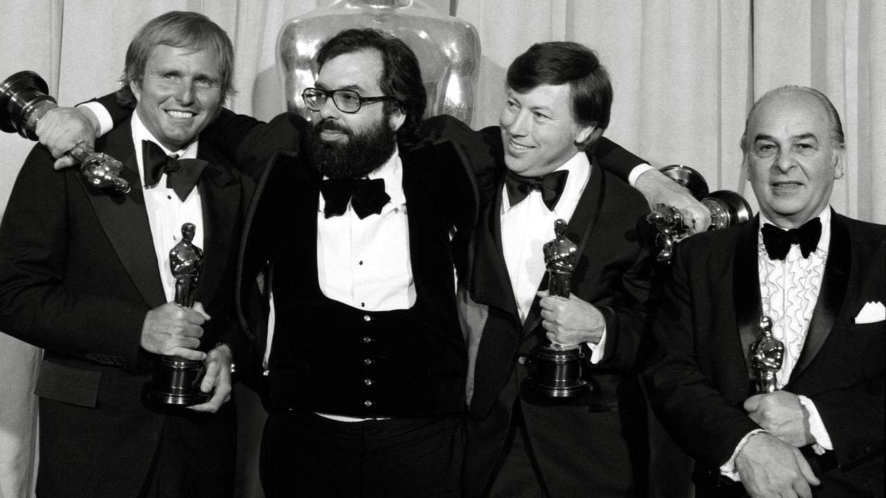 Auf einem Schwarz-Weiß-Bild stehen vier Männer nebeneinander und halten Oscar-Trophäen in der Hand.