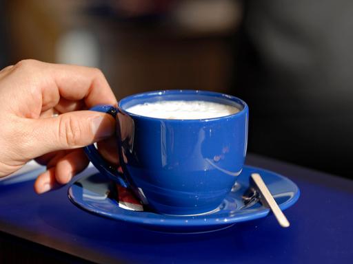 Mann hält eine Tasse Kaffee in der Hand